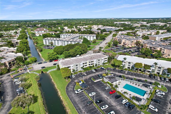 Aerial view of a residential complex with multiple buildings, parking areas, and a canal.