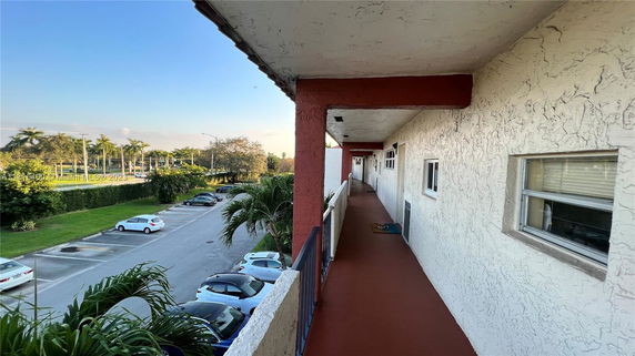 View from an apartment balcony overlooking a parking lot and street.