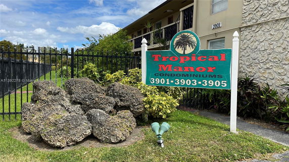 Front view of a condominium building with a sign reading 'Tropical Manor Condominiums.'
