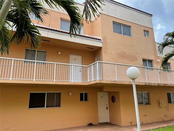 Front view of a multi-story building with a balcony and multiple windows.