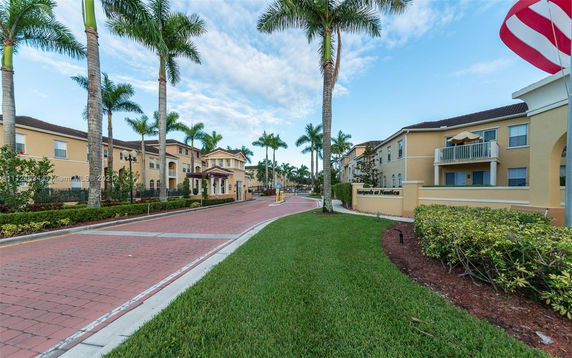 Front view of a multi-story residential complex with palm trees.