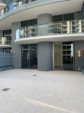 Front view of a modern multi-story building with curved balconies and glass railings.