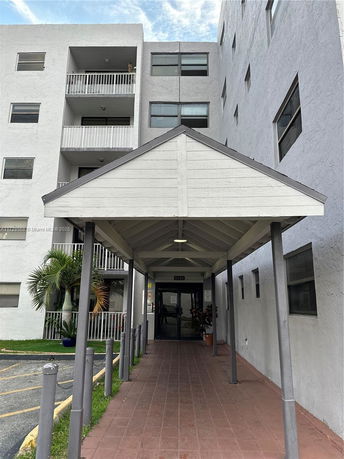 Front view of a multi-story residential building with balconies and an entrance canopy.