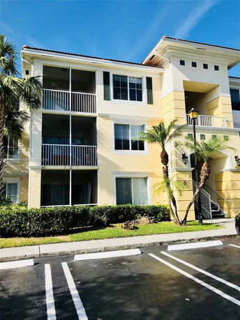 Front view of a multi-story residential building with balconies and a yellow facade.