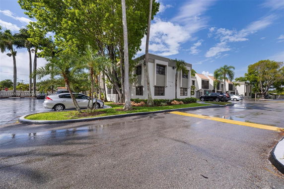 Front view of a multi-story residential building with adjacent parking area.