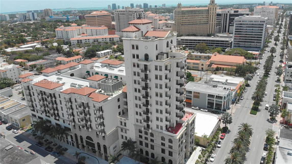 Aerial view of a multi-story building with balconies, surrounded by other buildings in an urban area.