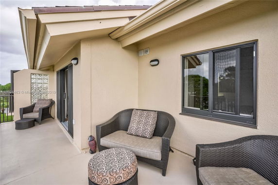 Rooftop seating area with cushioned chairs and a small table near sliding glass doors.