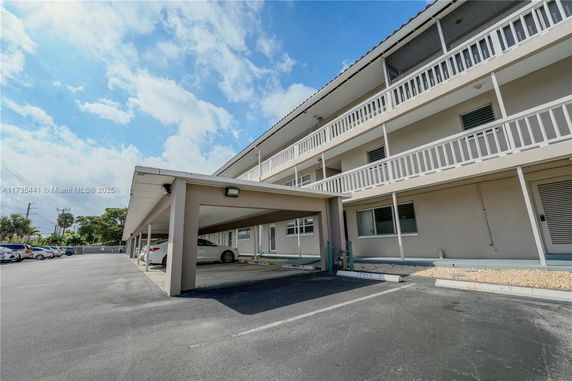 Covered outdoor parking area adjacent to a multi-story building.