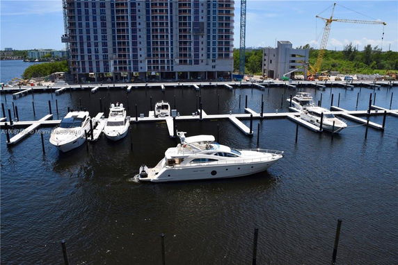 High-rise building under construction near a marina with several boats docked.