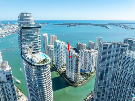 Aerial view of a coastal cityscape with multiple high-rise buildings and water in the background.