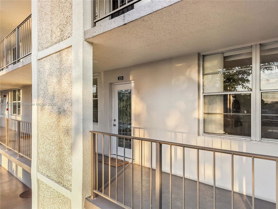 Exterior view of a building with a walkway and apartment entrance.