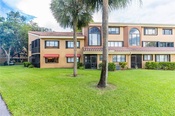 Front view of a multi-story residential building with a tiled roof and large windows.