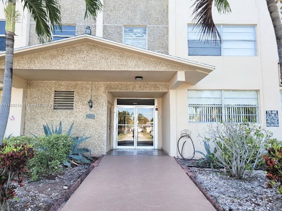 Front view of a multi-story building entrance with a covered porch and double glass doors.