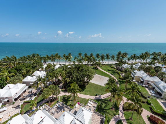Panoramic view of a beachfront area with palm trees and multiple white-roofed buildings.