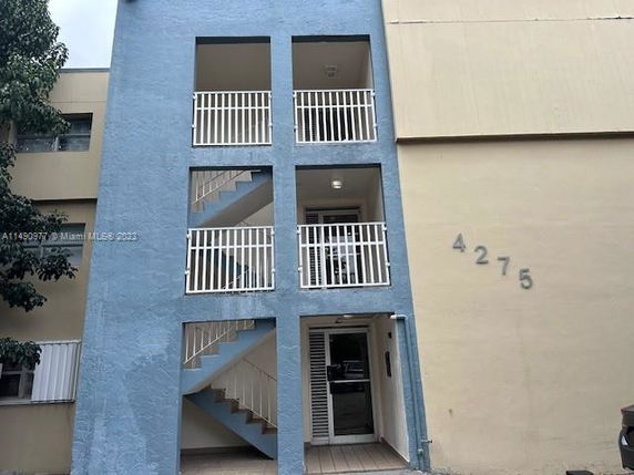 Front view of a multistory building with an exterior staircase and balconies.