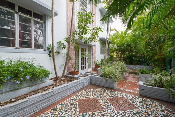 Front view of a building with tiled walkway and lush greenery.