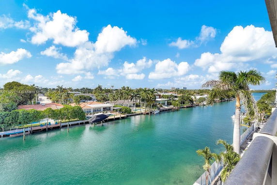 Panoramic view of waterfront residences with a clear blue canal and palm trees.