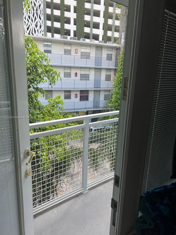 View through a doorway overlooking a multi-story building with balconies.