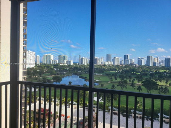 Panoramic view from a balcony overlooking a cityscape with tall buildings and greenery.