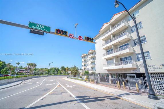 Front view of a multi-story building with balconies next to a road intersection.