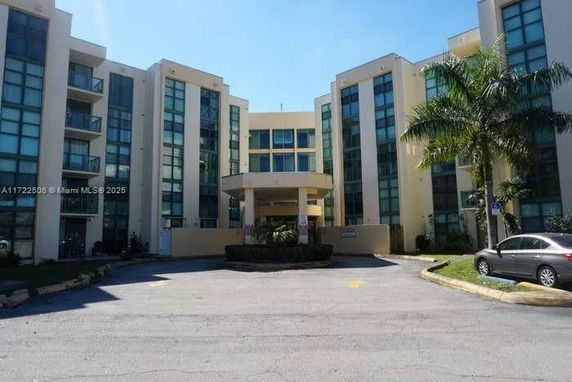 Front view of a multi-story building with glass windows and a circular entrance.