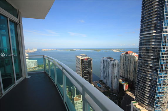 Panoramic view from a high-rise balcony overlooking a body of water and surrounding skyscrapers.