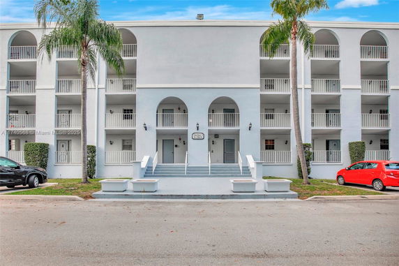 Front view of a multi-story building with balconies and a central entrance.