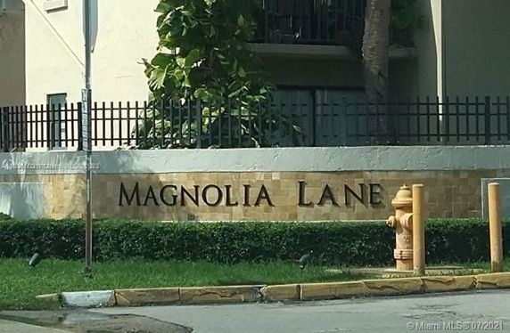 Front view of a building with a sign reading 'Magnolia Lane' and surrounding fence.