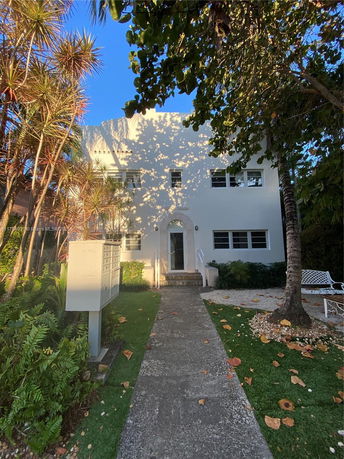 Front view of a two-story house with a white facade and several windows.