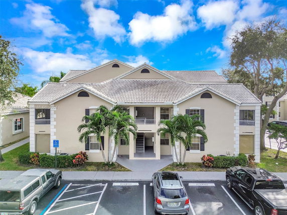 Front view of a multi-story residential building with a tiled roof and parking area.