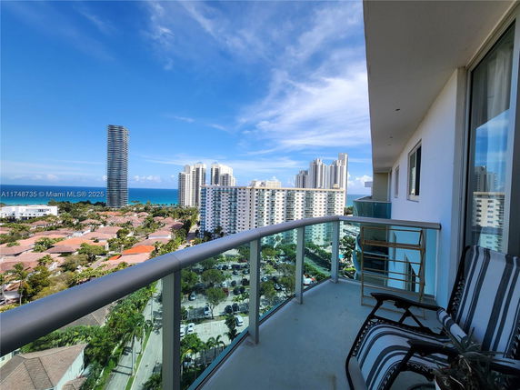 View from a balcony overlooking high-rise buildings and the ocean.