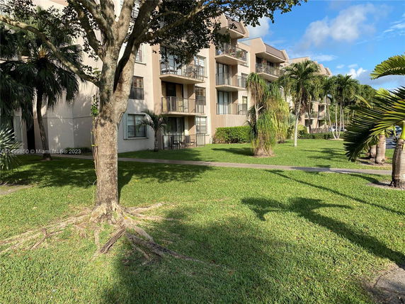 Front view of a multi-story apartment building with balconies and well-maintained lawn.