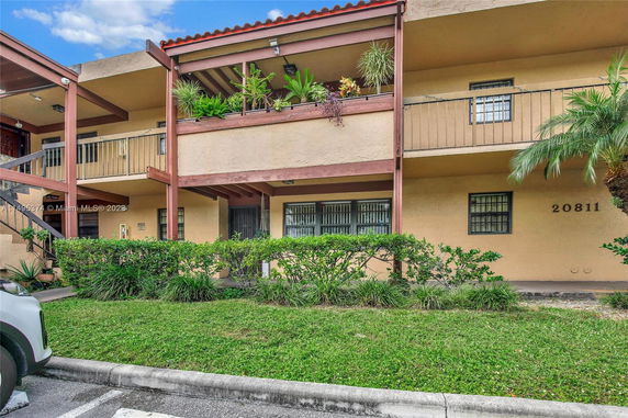 Front view of a two-story building with balconies and potted plants.