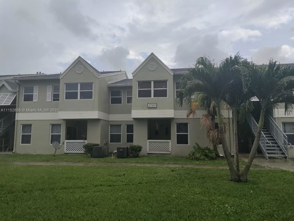 Front view of a two-story residential building with multiple windows and exterior staircases.