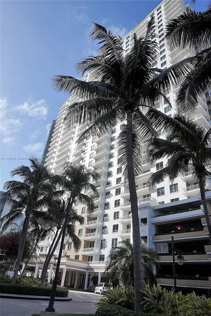 Front view of a tall white apartment building with balconies.