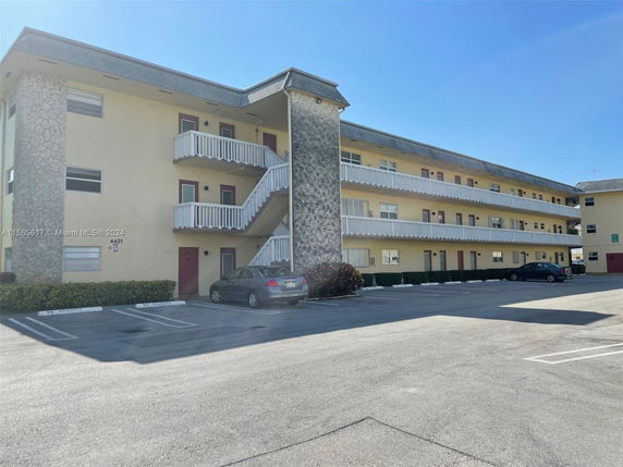 Front view of a three-story apartment building with stone and beige exterior.