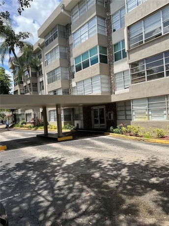 Front view of a multi-story apartment building with large windows and a covered entrance.