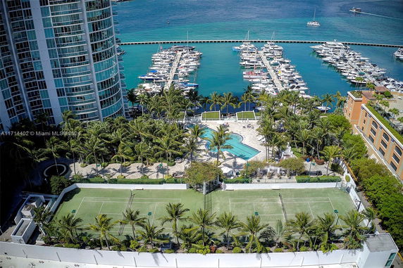 View of outdoor amenities with tennis courts and a pool, adjacent to a marina.