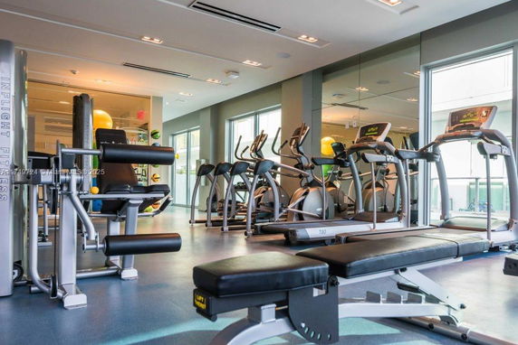 Room with exercise equipment including treadmills and weight machines.