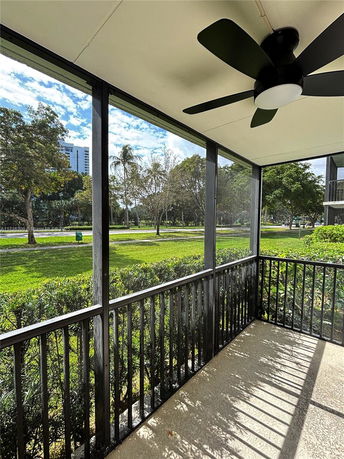 View of the surrounding area from a screened porch with a ceiling fan.