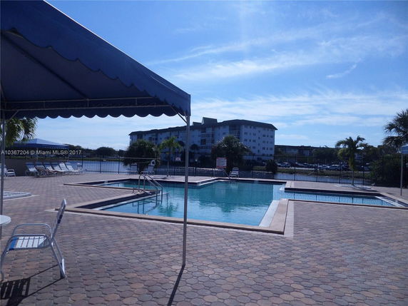 View of a swimming pool area with a multi-story building in the background.