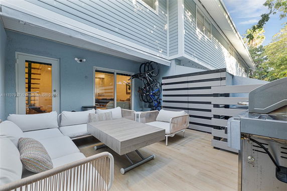 Outdoor patio area with seating and a grill next to a two-story building.