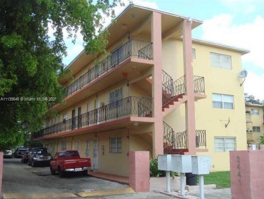 Front view of a three-story apartment building with external staircases and balconies.
