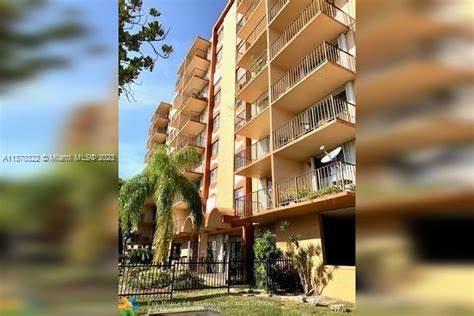 Front view of a multi-story apartment building with balconies and a gated entrance.