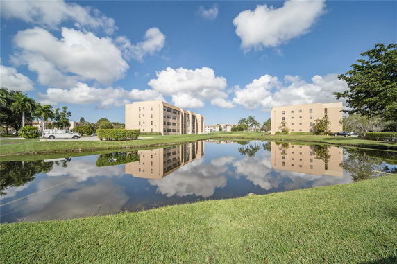View of multiple buildings with a reflective pond in the foreground.