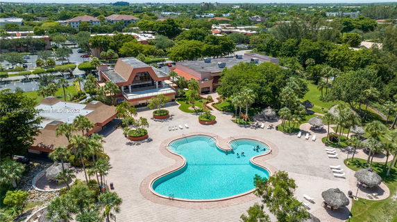 Aerial view of a swimming pool with surrounding deck area and nearby building.