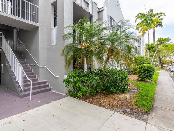 Front view of a multi-story building with balconies and outdoor stairs.