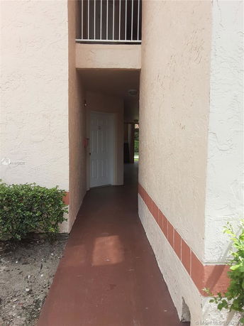 Entrance corridor of a residential building with a doorway and upper balcony.