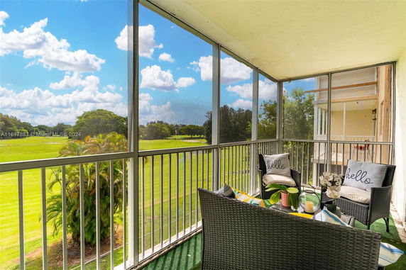 View from a screened balcony overlooking a grassy area with trees.