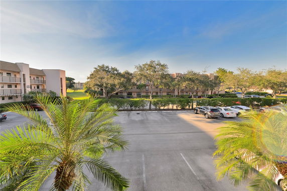 View of a parking area with cars and surrounding buildings.